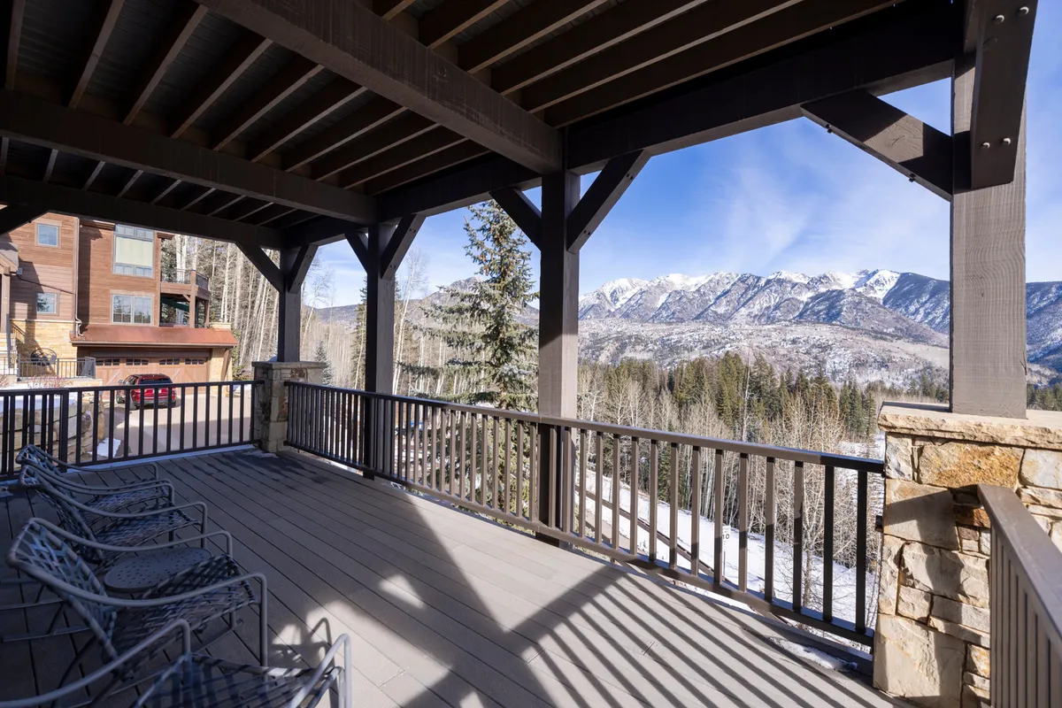 A tranquil exterior deck scene with metal chairs overlooking a sweeping mountain vista. The wooden beams and open layout evoke relaxation and immersive outdoor enjoyment, with the deck perfectly positioned for sunrise or sunset viewing.