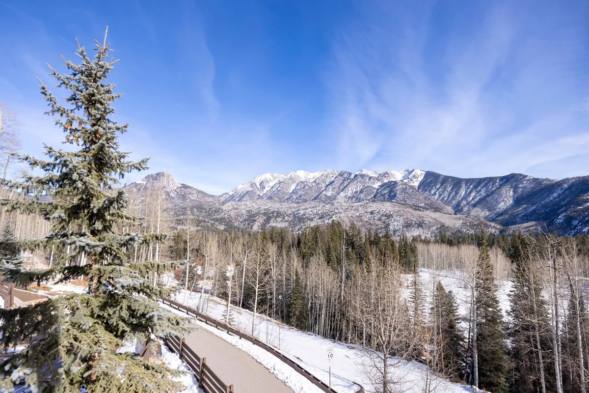 A panoramic view of snow-covered mountains and dense pine forests beneath a clear blue sky. The landscape radiates tranquility and adventure, hinting at hiking, skiing, and nature photography opportunities. The scene evokes the spirit of Durango’s great outdoors and its natural splendor.