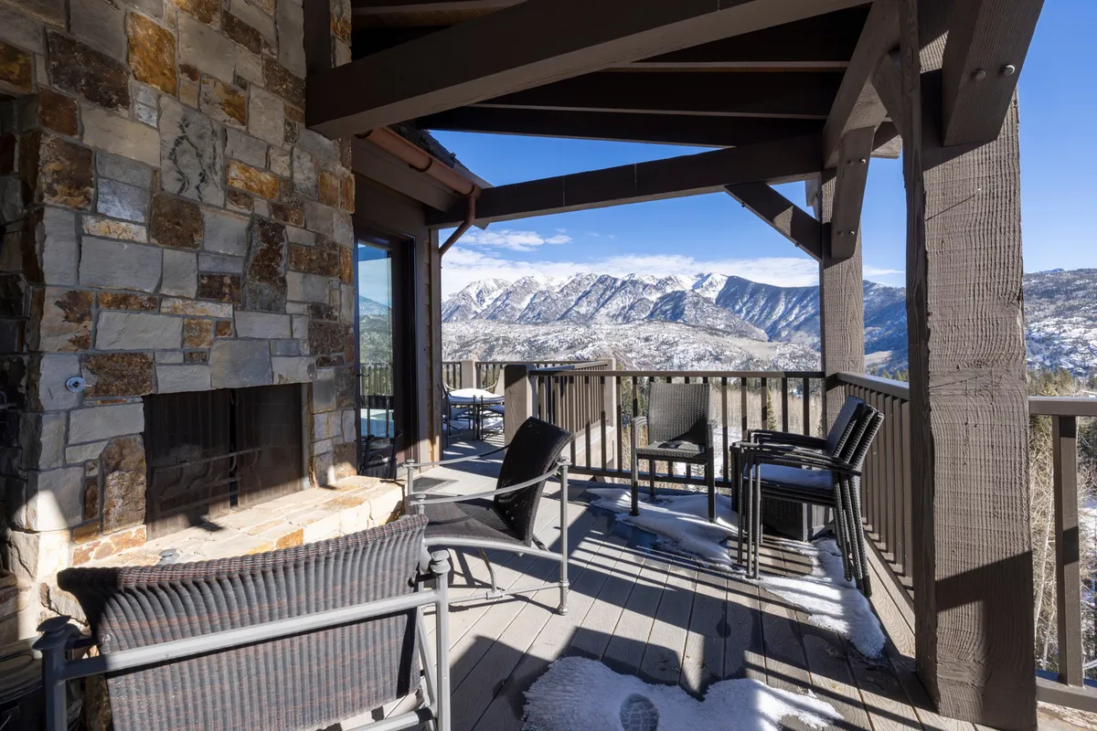 The outdoor stone fireplace sits at the heart of a cozy seating area, framed by majestic mountain scenery. Comfortable chairs invite guests to gather around the fire, perfect for evening relaxation or socializing under the stars.