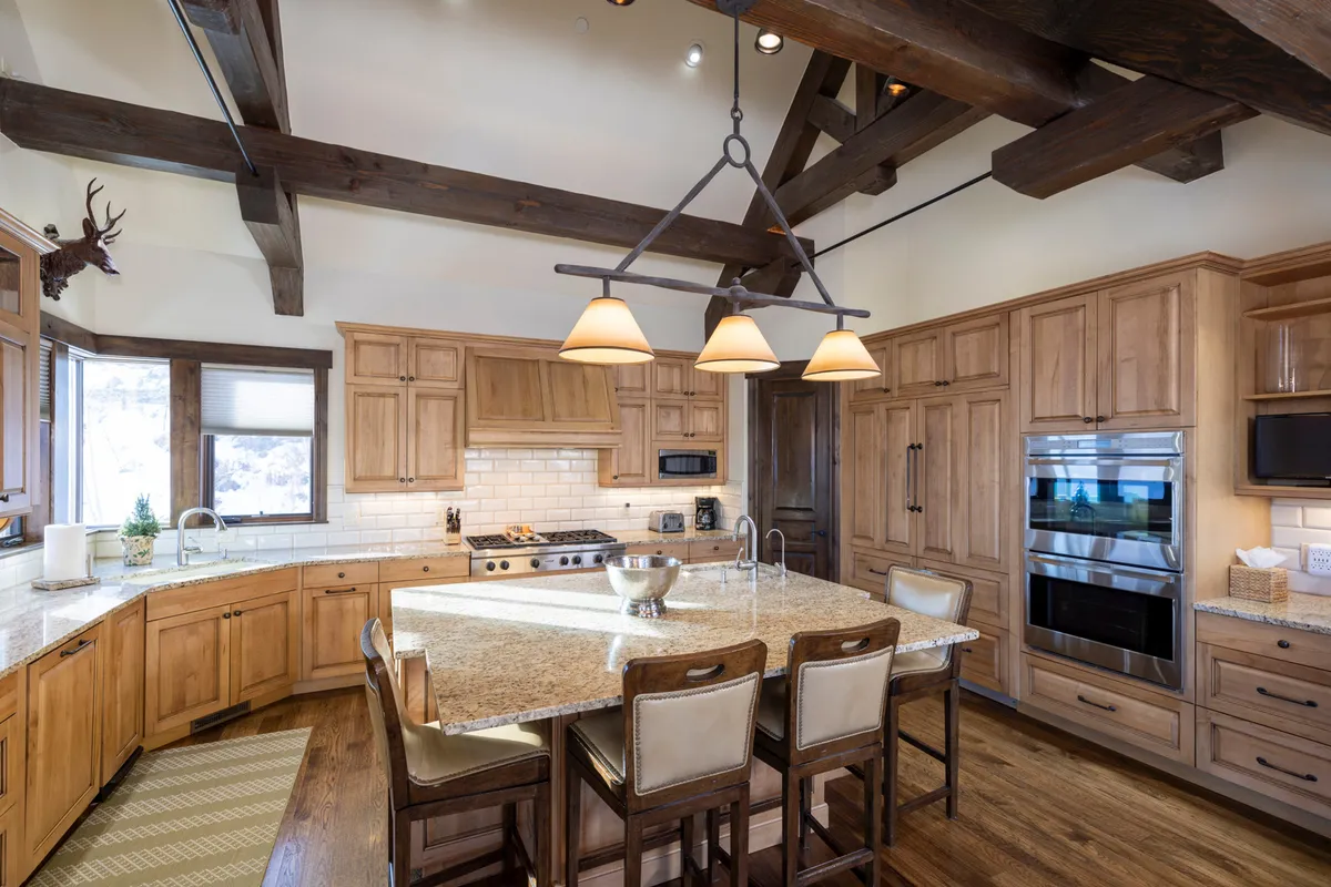 Here, a large central island with comfortable seating is complemented by rustic wooden beams and granite countertops. The kitchen exudes warmth and invites guests to participate in meal preparation or enjoy casual conversations with the chef.