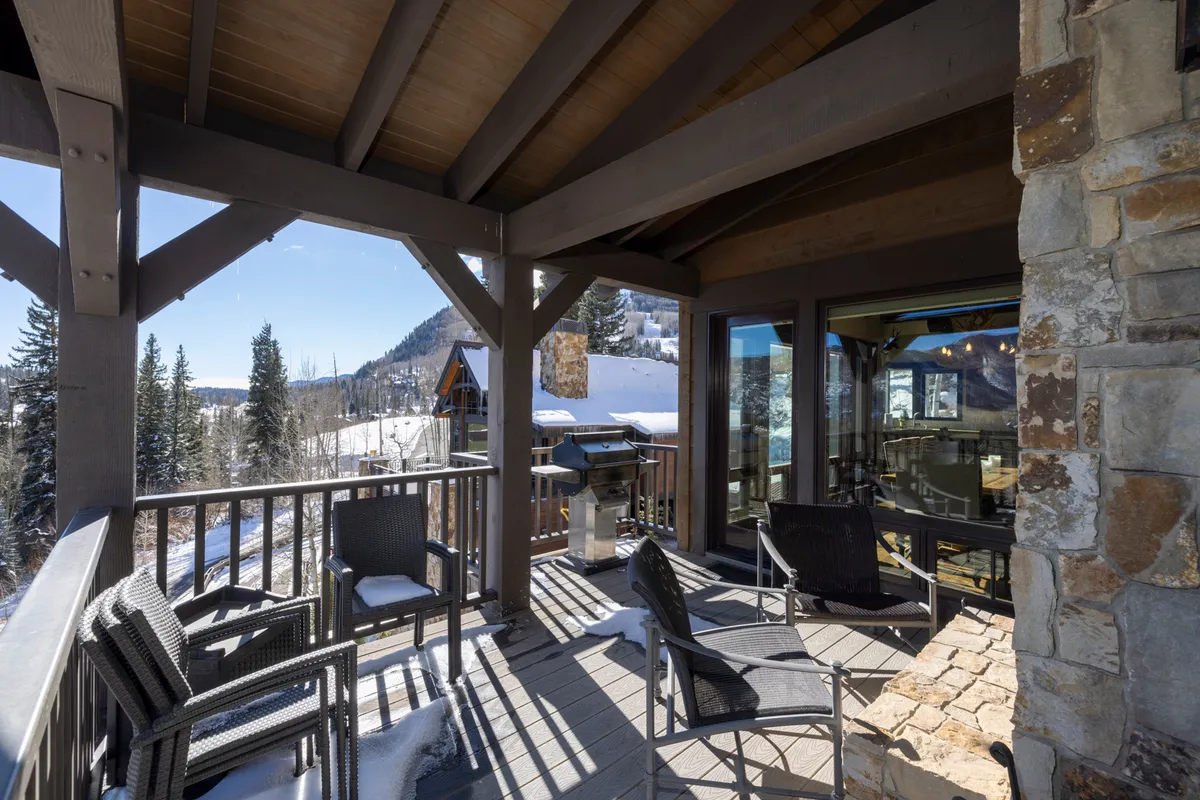 This inviting exterior scene features a comfortable outdoor seating area with a top-tier gas grill, all set before a stunning mountain view. The setting suggests a space designed for alfresco dining and lively gatherings.